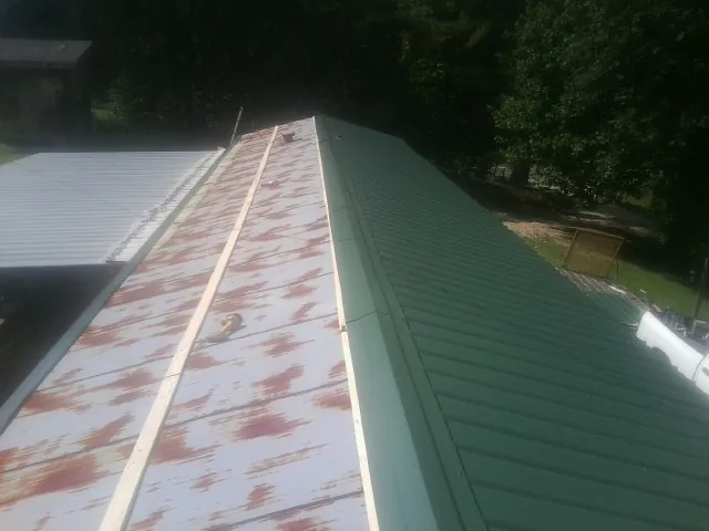 Old rusted panels beside newly installed green metal roofing — Wind Damage Roof Repair by Roofing Brothers in Eaton Rapids