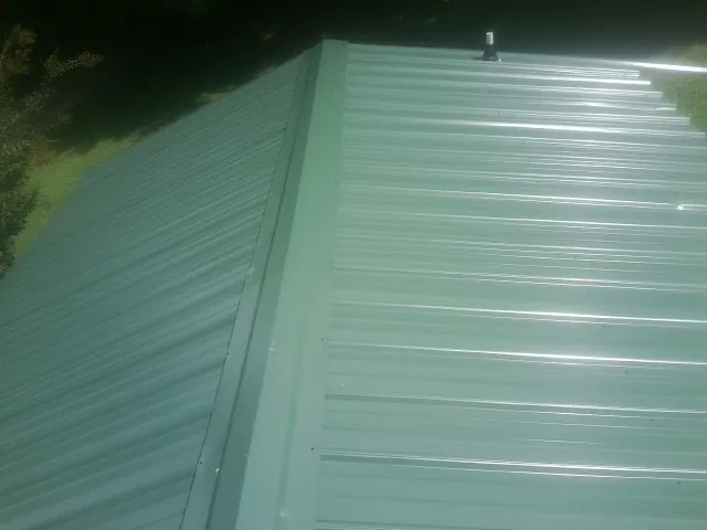 New green metal panels meeting at the ridge of a roof — Flat Roof Repair work by our crew in Eaton Rapids