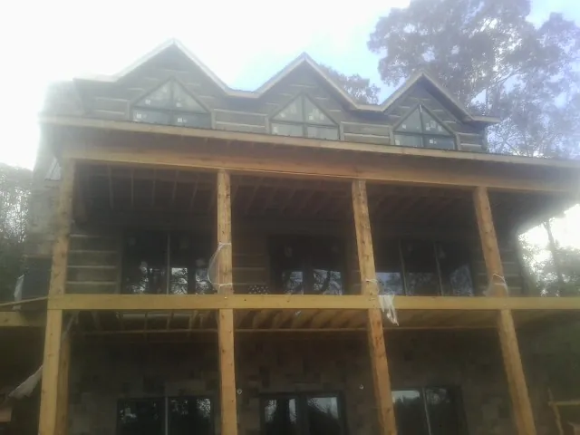 Dormers and porch framing on a large log home under construction — Roof Coating work by our crew in Eaton Rapids